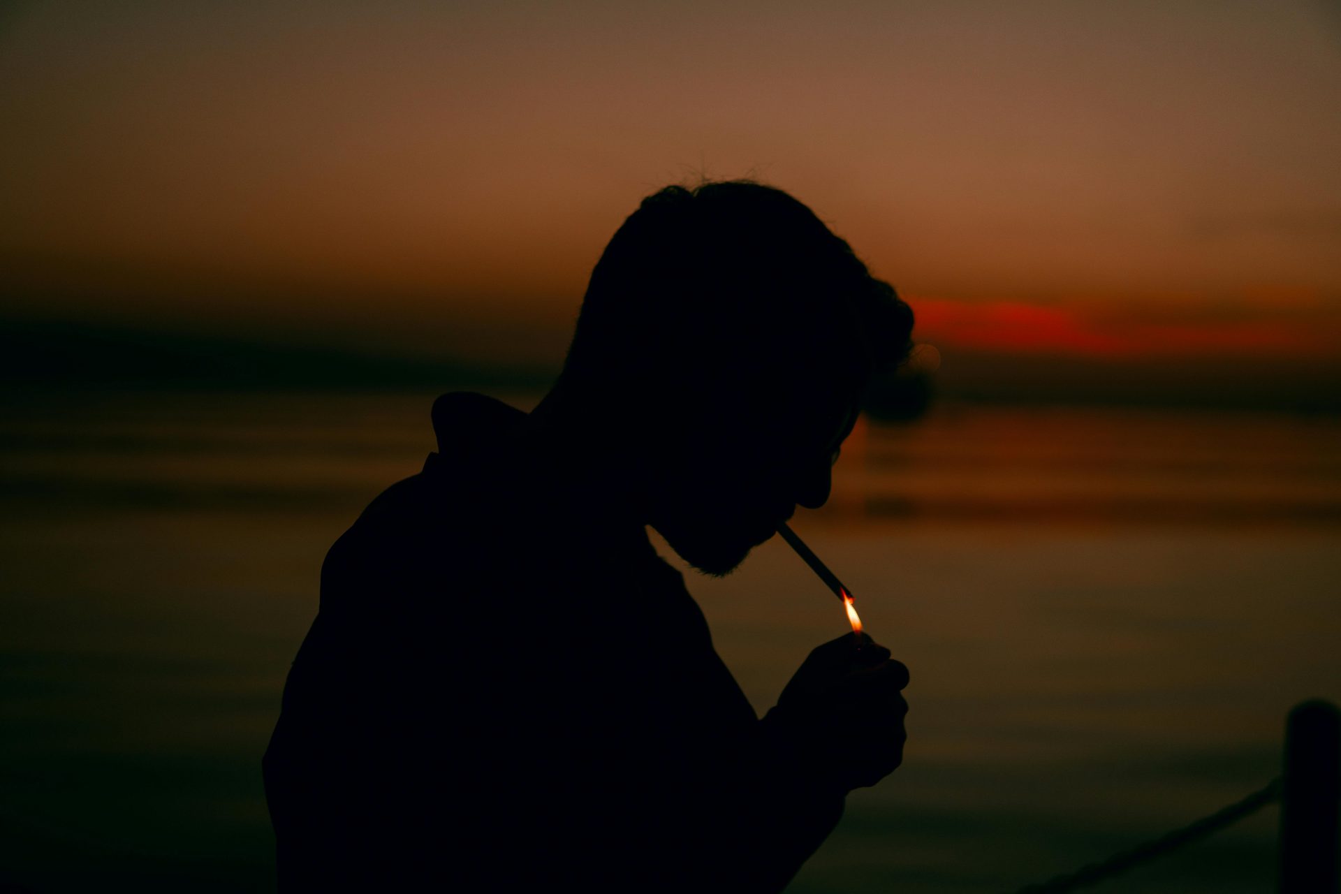 Une personne allume une cigarette au bord de la mer au crépuscule à Istanbul, en Turquie.