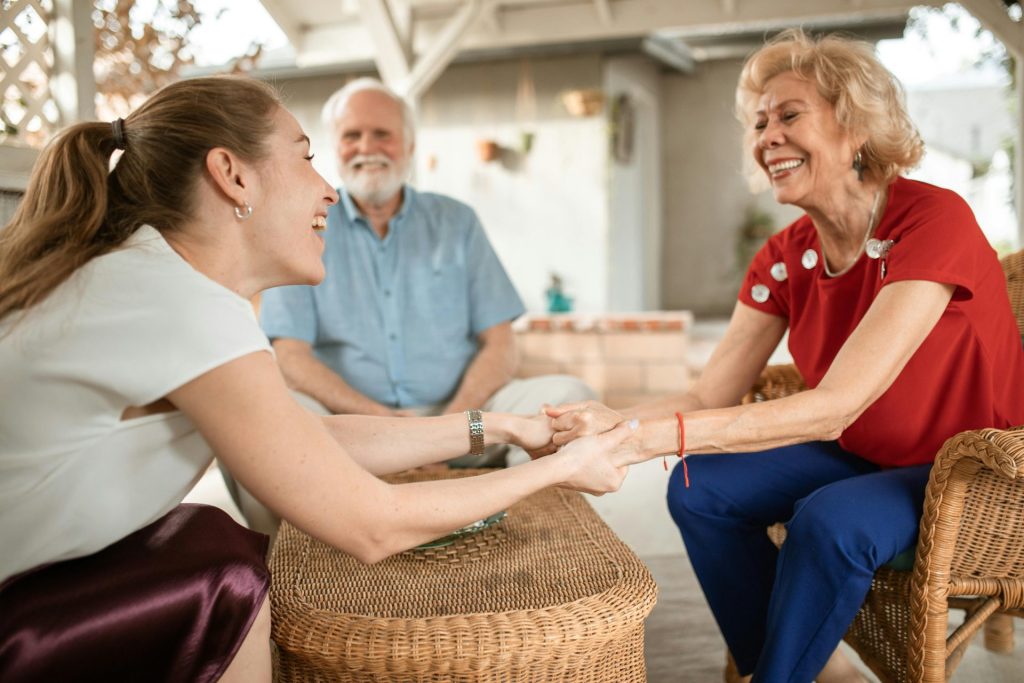 Trois membres de la famille profitent d'une conversation joyeuse à l'extérieur, partageant des rires et des sourires.