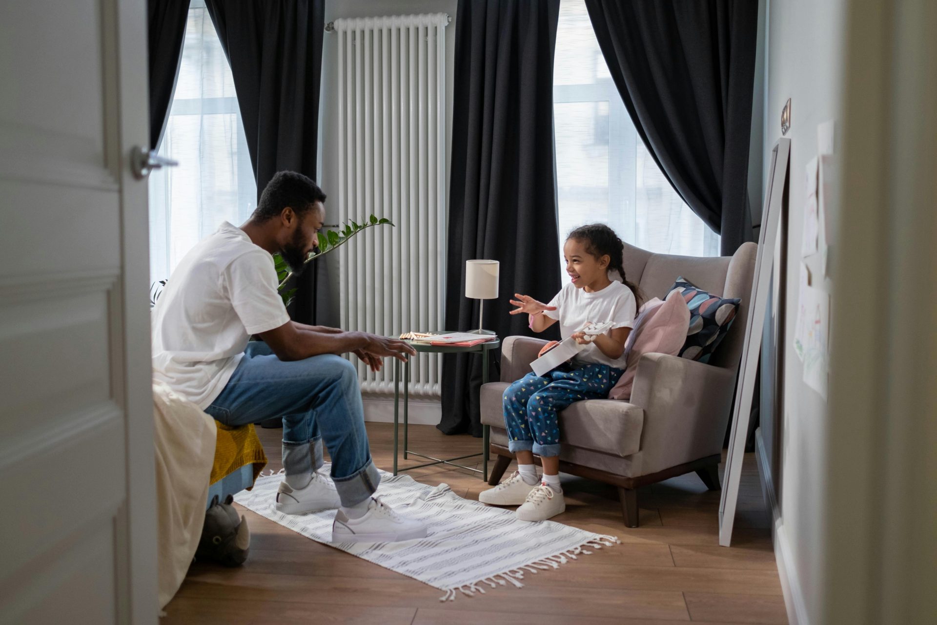 Un père et sa fille discutent dans un cadre intérieur chaleureux, favorisant ainsi les liens familiaux.
