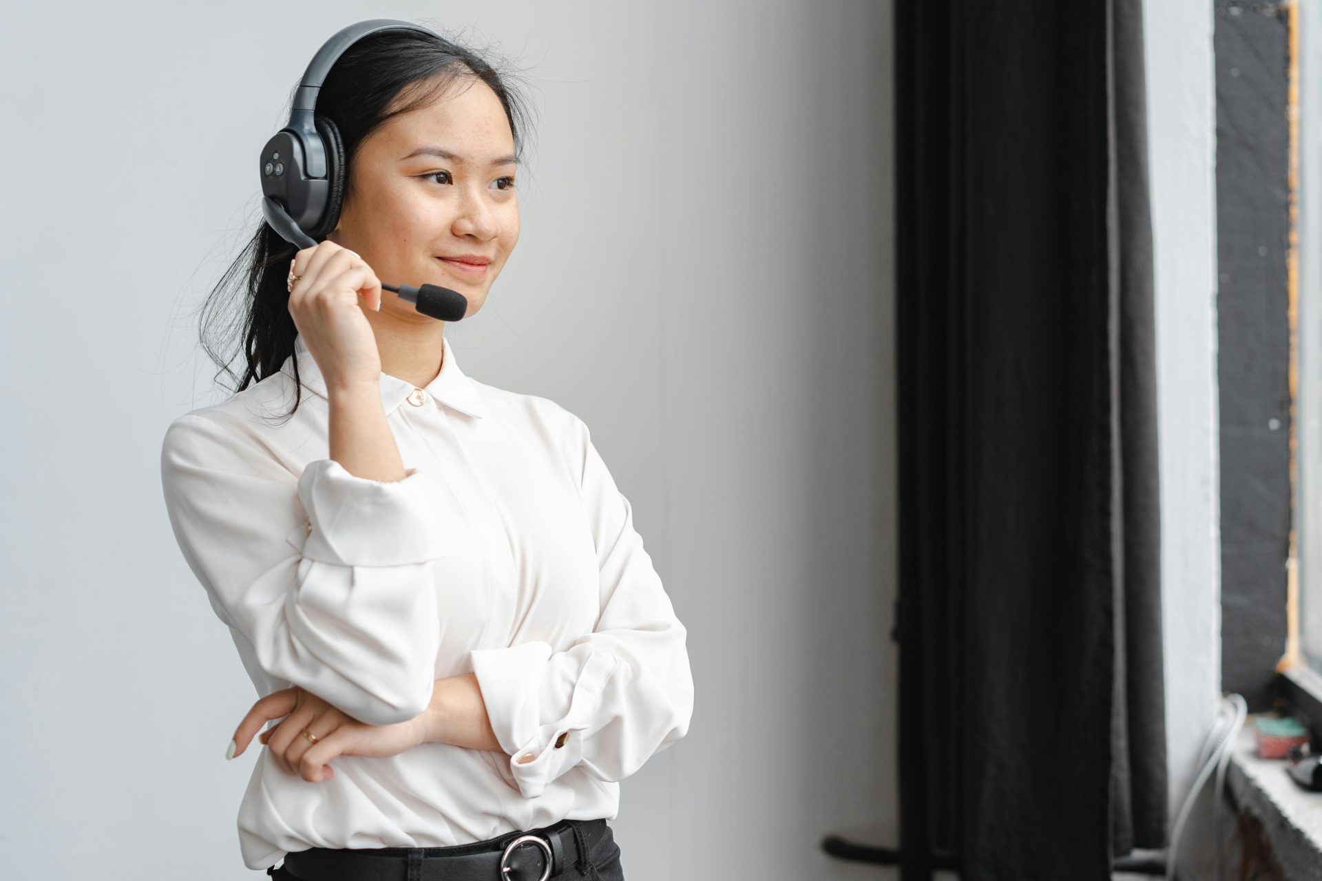 Femme asiatique professionnelle avec un casque fournissant un support client dans un environnement de bureau.